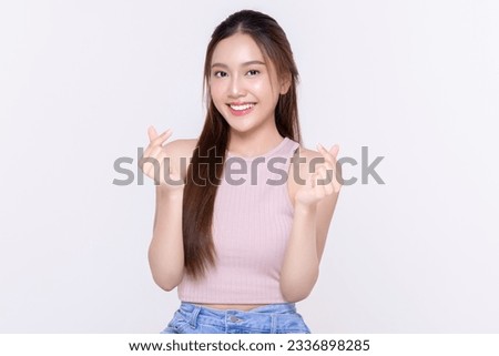 Beautiful young Asian woman shows mini heart fingers on isolated white background. Facial and skin care concept for commercial advertising.