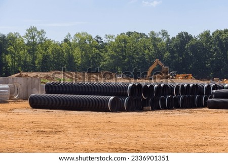 On construction site, stacks of large black plastic pipes ready for sewerage installation. Royalty-Free Stock Photo #2336901351