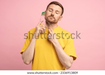 Overheated tired middle aged man suffers from heat, puts bottle of cold water to neck. Exhausted guy trying to cool down after sports training in hot summer day, feels dehydrated and thirsty.  Royalty-Free Stock Photo #2336913809