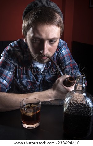 Bearded hipster with tobacco pipe and cognac.