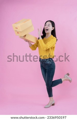 Full body portrait of Asian online seller with long hair Throw a cardboard box up in the picture. Shocked and excited, wearing a coat, jeans, and high heels. photo shoot in the pink scene studio