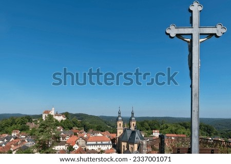 Overview of the pilgrimage site of Gößweinstein in Franconia with a Christian cross at the right edge of the picture and a blue, cloudless sky in fine summer weather