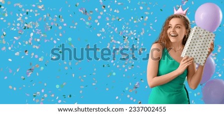 Happy young woman with gift celebrating Birthday on light blue background with falling confetti. Banner for design
