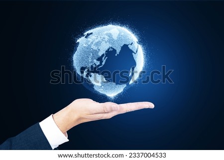 Close up of man's hand holding glowing globe hologram on blurry blue background. Digital earth and metaverse concept