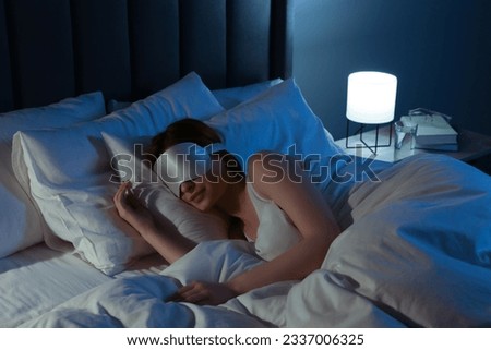 Woman with mask sleeping in bed at night Royalty-Free Stock Photo #2337006325