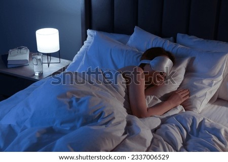 Woman with mask sleeping in bed at night Royalty-Free Stock Photo #2337006529
