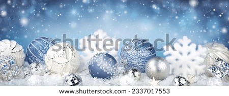 Winter snowy background with Christmas toys, snowdrifts, with beautiful light and snow flakes on the blue sky in the evening, banner format, copy space. Christmas decoration.