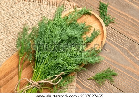 Board with bunch of fresh dill on wooden background Royalty-Free Stock Photo #2337027455