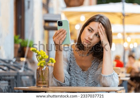 Pretty young woman use smartphone typing browsing, loses becoming surprised sudden lottery results, bad news, fortune loss, fail. Girl walking in urban city cafe terrace outdoors. Town lifestyles Royalty-Free Stock Photo #2337037721
