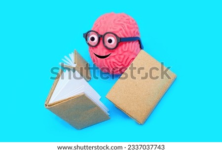 Cute human brain character adorned with googly eyes and nerdy glasses, engrossed in reading a book. Learning and curiosity related concept.