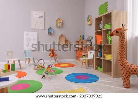 Child`s playroom with different toys and furniture. Cozy kindergarten interior Royalty-Free Stock Photo #2337039025