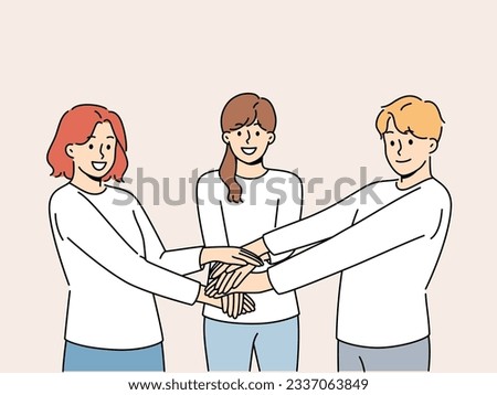 Friendly team of people holding hands demonstrate cohesion and unity, wanting to achieve goals together. Team of young guy and two girls carrying out volunteer or charitable activities Royalty-Free Stock Photo #2337063849