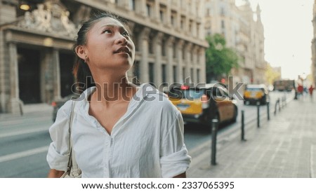 Young woman walks down the street and looks around Royalty-Free Stock Photo #2337065395