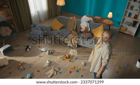Mother standing and looking sad around the scattered toys in the living room Royalty-Free Stock Photo #2337071299