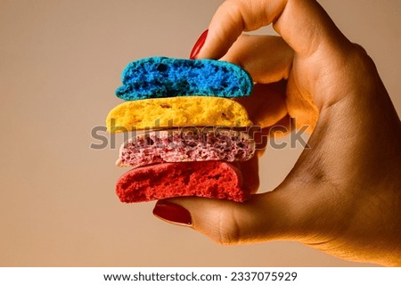 Closeup view of four sweet multicolored blanks of macaron broken in half in female hands. Space for text. Confectionery business concept