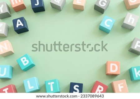 Wooden cubes with English letters on a pastel green background. ABC learning, education and language concept