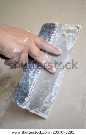 Putty walls with a spatula. Leveling the walls with a spatula is a man's hand. Spatula in hand.