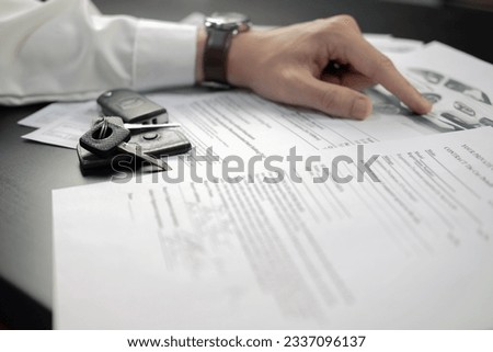 Man signing car insurance document or lease paper. Writing signature on contract or agreement. Buying or selling new or used vehicle. Car keys on wooden table. Warranty or guarantee. Royalty-Free Stock Photo #2337096137