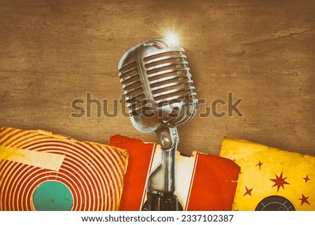 Retro styled image of an authentic vintage microphone with old record albums
