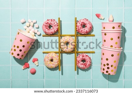 Glazed donuts, straws and paper cups with marshmallows on blue background, top view
