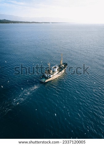 Aerial view of fishing boat surrounded by black-headed gulls in coming back to the port in Black Sea. Vertical picture