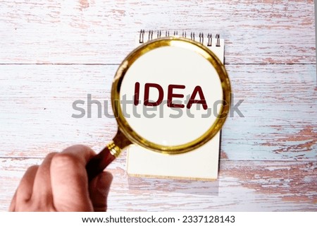 idea word written text through a magnifying glass on a paper notebook