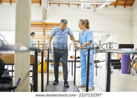 Smiling physiotherapist assisting senior man to walk during movement therapy at rehabilitation center Royalty-Free Stock Photo #2337132397