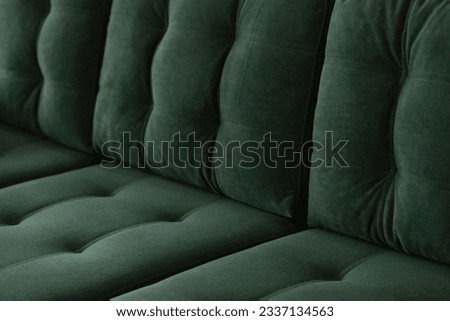 Soft vintage sofa in green velor with a quilted seat and a back of stitched cushions. Part of stylish furniture covered with plush fabric in emerald color close-up. Royalty-Free Stock Photo #2337134563