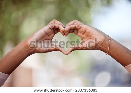 Woman, heart hands and love in nature for compassion, romance or care against a blurred background. Closeup of female person with loving symbol, gesture or sign for valentines day in the outdoors