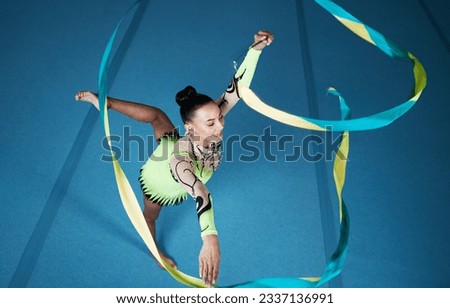 Rhythmic gymnastics, woman in gym and ribbon with balance, action with performance and fitness. Competition, athlete and female gymnast, creativity and art with dancing routine and energy at arena