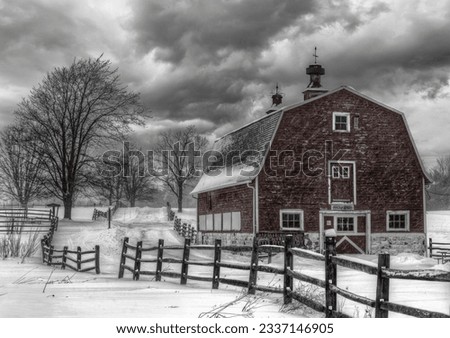 A grayscale shot of a barn in the snowy countryside under a gloomy sky Royalty-Free Stock Photo #2337146905
