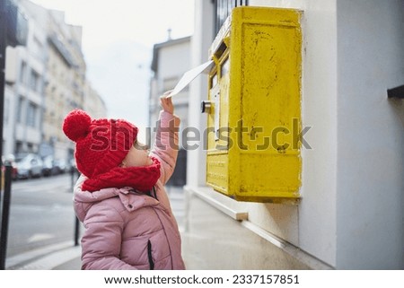 Adorable preschooler girl putting letter in yellow post box on a street of Paris, France Royalty-Free Stock Photo #2337157851