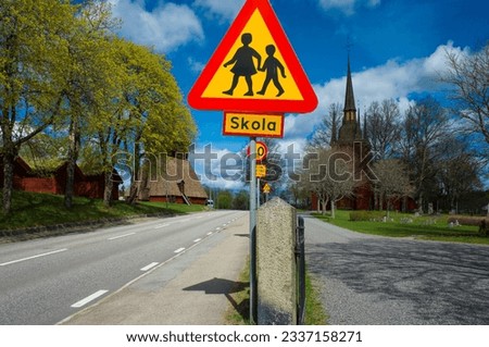 Swedish red and yellow traffic sign warning for children crossing the road in the old town of Kopparberg, Sweden