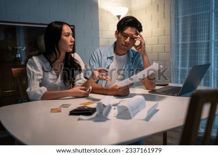 Asian young depressed couple having argument while checking money debt. Attractive new marriage man and woman looking frustrated to paperwork and bill, feel worried about financial problem in house. Royalty-Free Stock Photo #2337161979