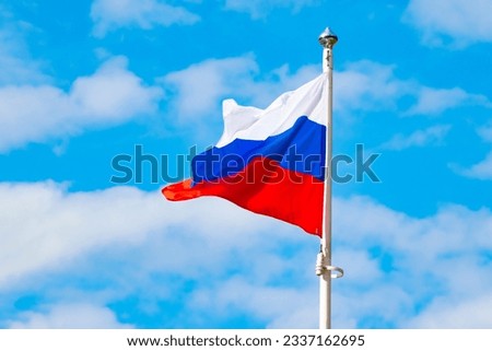 flag of the Russian Federation on a flagpole. Blue clear sky with clouds. close-up