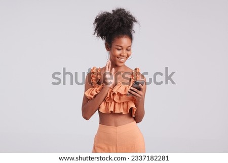 Exuding studio chic, a girl in an orange shirt captures stunning fashion moments using her smartphone during the shoot.
