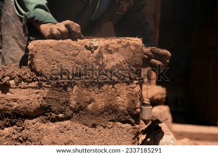 Man building with his hands an adobe house with adobe bricks and mud. Llachon region of Lake Titicaca in Peru. Royalty-Free Stock Photo #2337185291