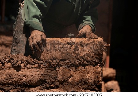 Man building with his hands an adobe house with adobe bricks and mud. Llachon region of Lake Titicaca in Peru. Royalty-Free Stock Photo #2337185307