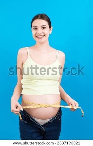 pregnant woman using tape measure to check baby development and the growth of belly. Inch measurement.