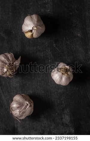 Fresh garlic bulbs on black background. Flat lay. Top view. Food concept. Dark mood food photography.