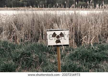 Radiation hazard sign next to a lake with radioactive waste