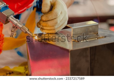 Close up: welder hands using portable handheld laser welding machine. Manufacturing, industrial, equipment, technology and metalworking concept Royalty-Free Stock Photo #2337217589