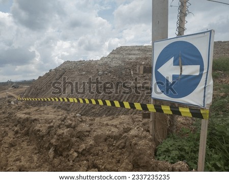 Signposts with barricades against a background of piles of earth, road closure concept photo