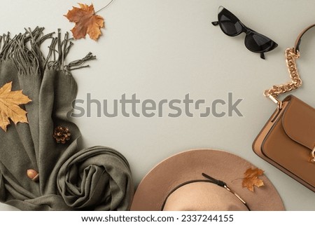Stylish seasonal accessories. Top view shot presenting a trendy felt hat, cozy scarf, elegant gloves, and a chic handbag on light grey background with empty frame for fashion-forward promotions Royalty-Free Stock Photo #2337244155