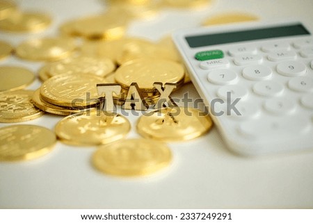 Flat wooden text written "TAX", with many crypto coins with a calculator beside, Close up, Crypto concept.