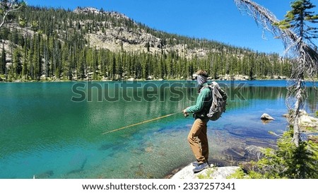 Adult Male Hiker Fishing High Alpine Lake With Mountain Background Royalty-Free Stock Photo #2337257341