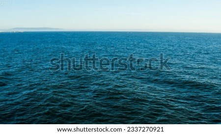 Aerial view to ocean waves. Blue water background. Coast with waves as a background from top view. Blue water background from drone. Summer seascape. Splashing Waves. Blue clean wavy sea water.