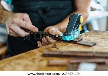 Soft focus of unrecognizable craftsman carving part for Spanish flamenco guitar on workbench during work in luthier workshop