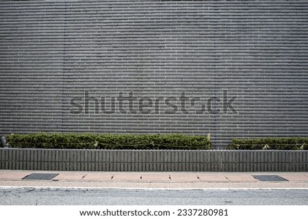 Frontal view of a modern gray brick facade with sidewalk and street in the foreground. Royalty-Free Stock Photo #2337280981