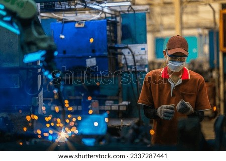 Asian worker working in old chinese factory in robot auto welding machine section and welding for assembly matal part, China